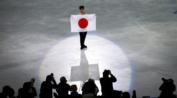 Ein Eiskunstläufer hält die japanische Flagge auf dem Eis.