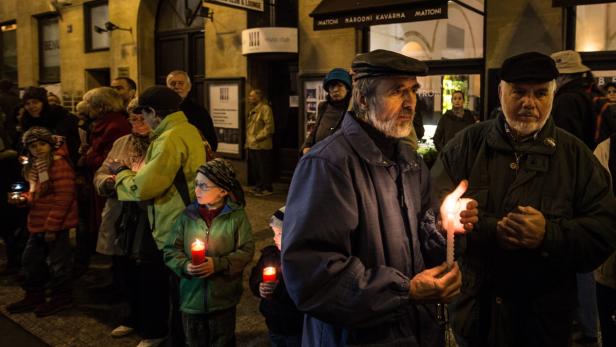Eine Gruppe von Menschen hält Kerzen in der Hand.