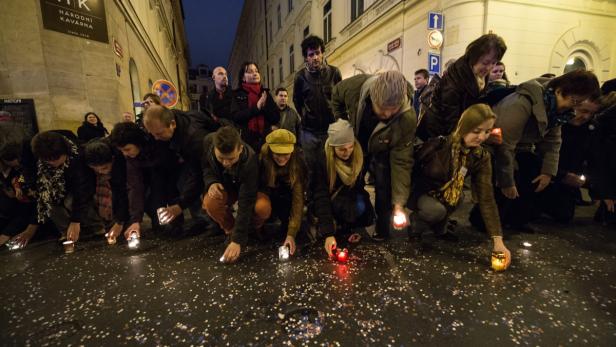 Eine Gruppe von Menschen zündet Kerzen auf einer Straße an.