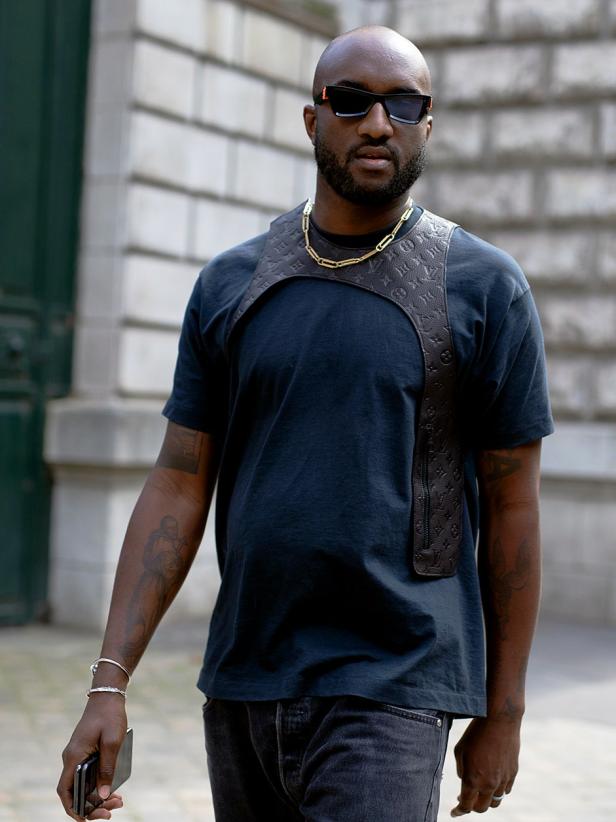 Ein Mann mit Sonnenbrille und einem Louis-Vuitton-Ledergeschirr über einem T-Shirt.