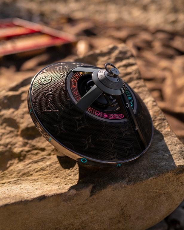 Ein Louis Vuitton Horizon Light Up Lautsprecher liegt auf einem Stein.