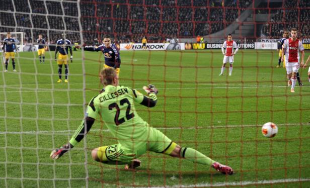 Ein Fußballspieler schießt einen Elfmeter auf das Tor, während der Torwart versucht, den Ball abzuwehren.
