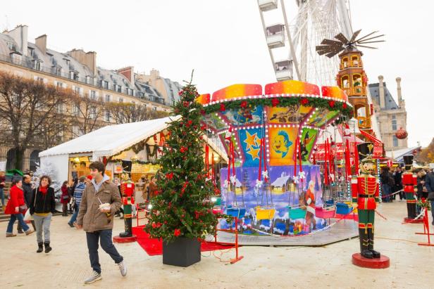 Ein Weihnachtsmarkt in Paris mit einem Karussell, einem Weihnachtsbaum und einem Riesenrad.