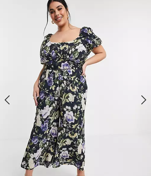 Eine Frau trägt einen floral gemusterten Jumpsuit mit weitem Bein.