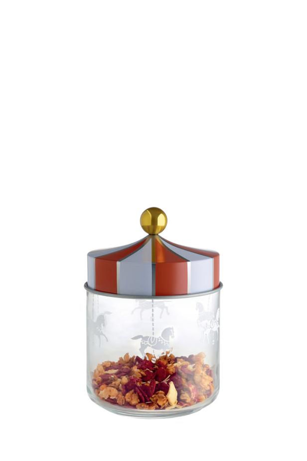 Ein Glasbehälter mit Karussellpferden und einem rot-silber gestreiften Deckel, gefüllt mit Granola.