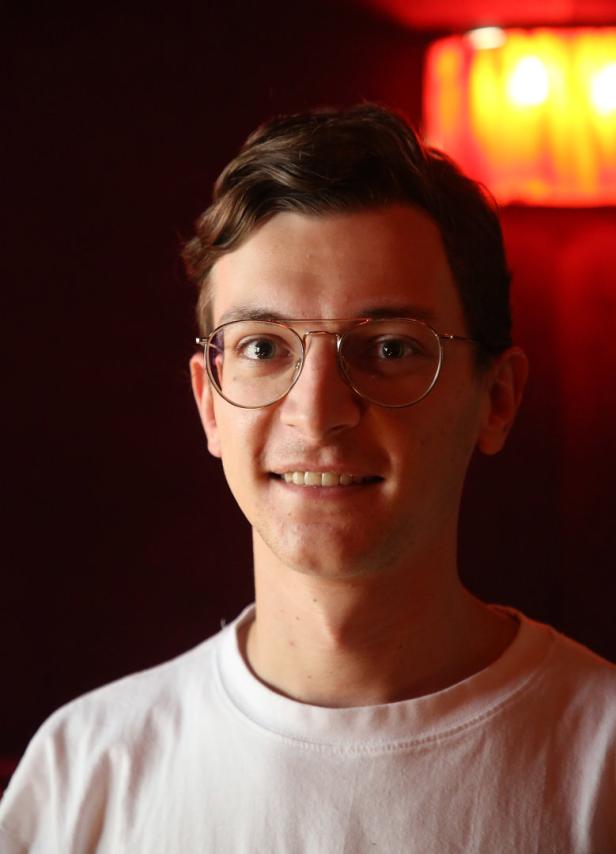 Ein junger Mann mit Brille lächelt in die Kamera.
