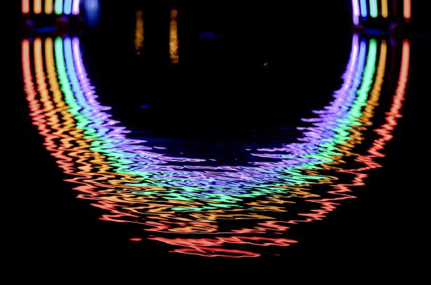 Das farbenfrohe Licht spiegelt sich im dunklen Wasser.