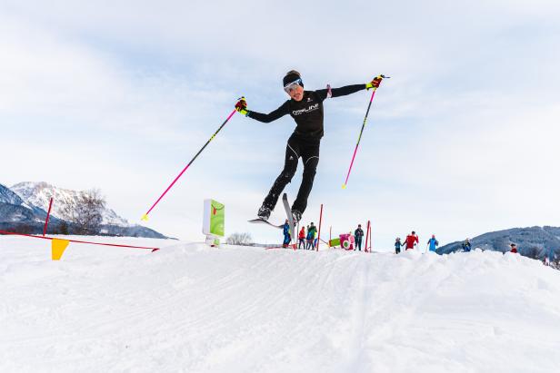 Eine Skifahrerin springt über eine Schanze vor einer Zuschauermenge.