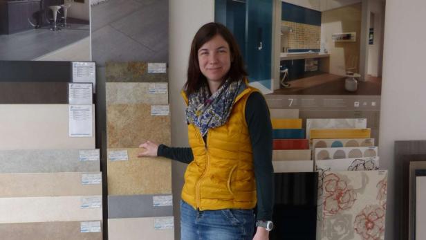 Eine Frau steht in einem Geschäft vor einer Auswahl an Fliesen.