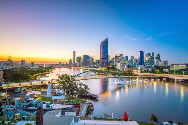 Blick auf die Skyline von Brisbane bei Sonnenuntergang mit Fluss und Brücken.