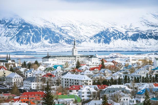 Blick auf Reykjavík mit schneebedeckten Bergen im Hintergrund.