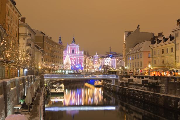 Blick auf Ljubljana im Winter mit dem Fluss Ljubljanica und der Franziskanerkirche im Hintergrund.