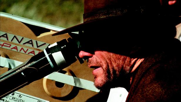 Ein Mann mit Hut blickt durch eine Panavision-Filmkamera.