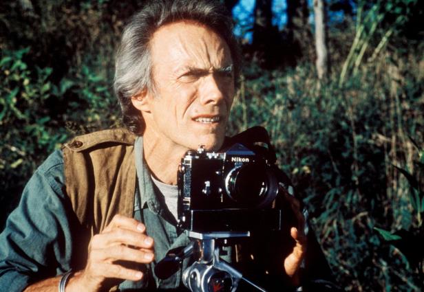 Clint Eastwood mit einer Nikon-Kamera auf einem Stativ in der Natur.