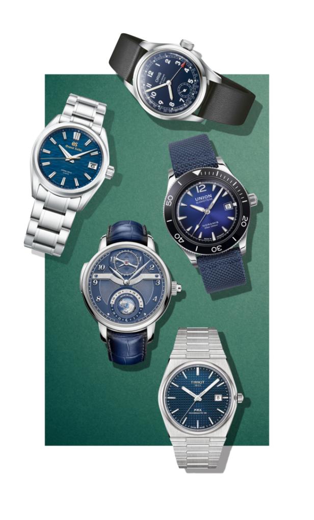Eine Auswahl verschiedener Armbanduhren mit blauen Zifferblättern auf einem grünen Hintergrund.