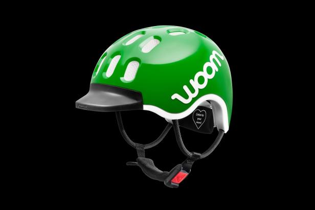 Ein grüner Fahrradhelm der Marke Woom vor schwarzem Hintergrund.