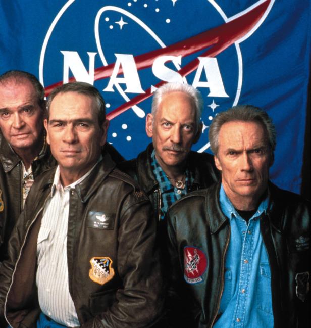 Die Schauspieler Tommy Lee Jones, Donald Sutherland, James Garner und Clint Eastwood vor einem NASA-Logo.