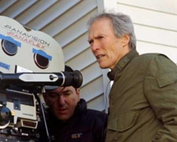 Clint Eastwood steht neben einer Panavision-Kamera am Set.
