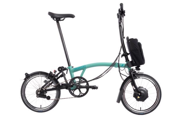 Ein mintgrünes Brompton-Faltrad mit schwarzem Gepäckträger und Schutzblechen vor einem weißen Hintergrund.