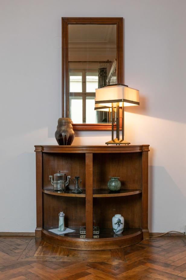 Ein Holzregal mit verschiedenen Vasen und einer Lampe unter einem Spiegel.