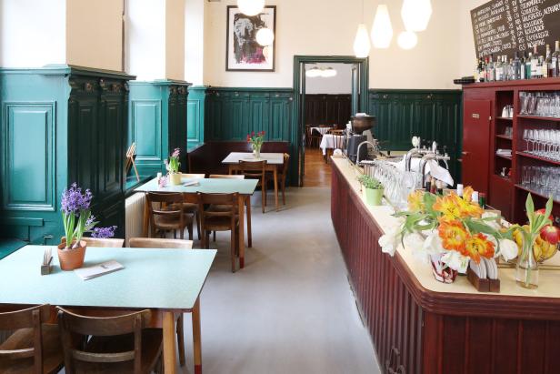 Innenansicht eines traditionellen Wiener Kaffeehauses mit Tischen, Stühlen und einer Bar.