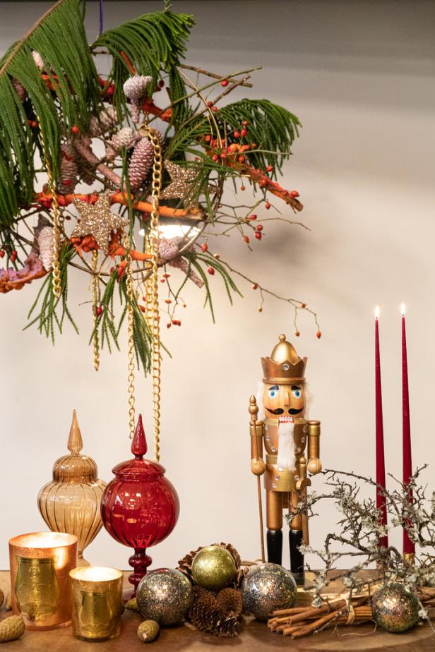 Ein Nussknacker steht neben roten Kerzen und weihnachtlicher Dekoration.