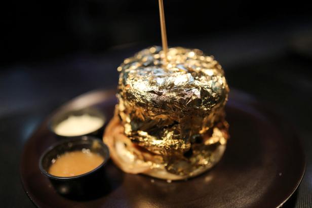 Ein mit Blattgold überzogener Burger auf einem Teller mit zwei Saucen.