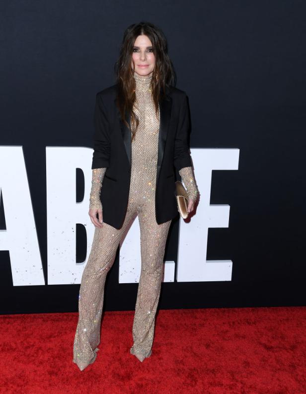 Sandra Bullock in einem glitzernden Overall und Blazer auf dem roten Teppich.