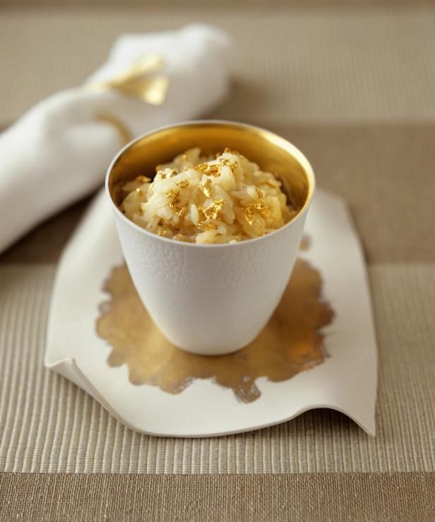 Ein weißes Schälchen mit Reis, dekoriert mit Blattgold, steht auf einem goldenen Untersetzer.
