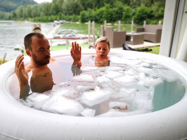 Ein Mann und eine Frau sitzen in einem mit Eis gefüllten Whirlpool im Freien.