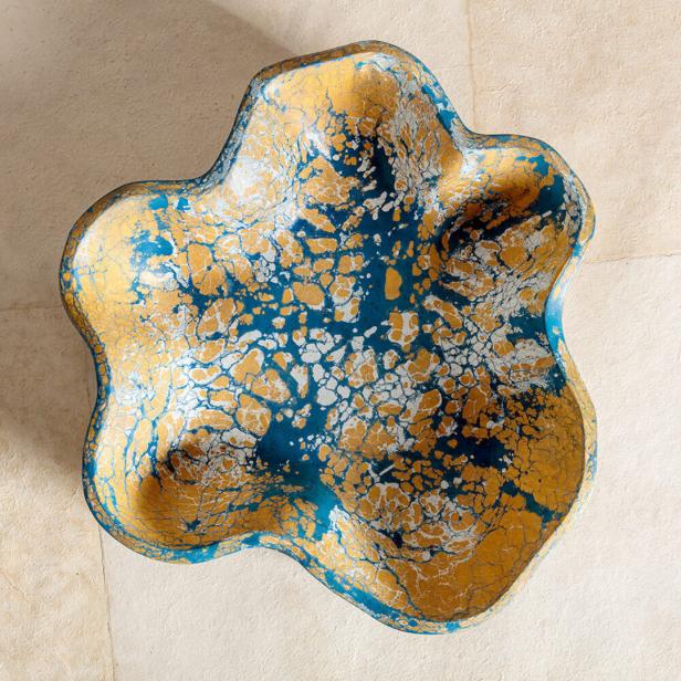 Eine dekorative Schale mit blauer, goldener und weißer Marmorierung liegt auf einem Tisch.