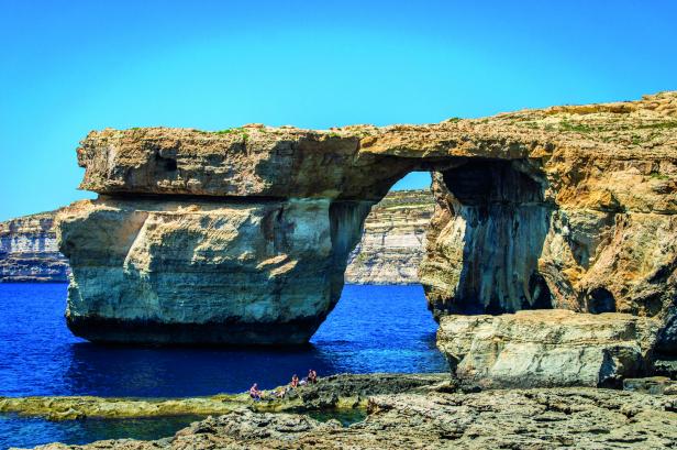 Die Azure Window, ein natürliches Felsentor auf Gozo, Malta, mit Personen im Vordergrund.