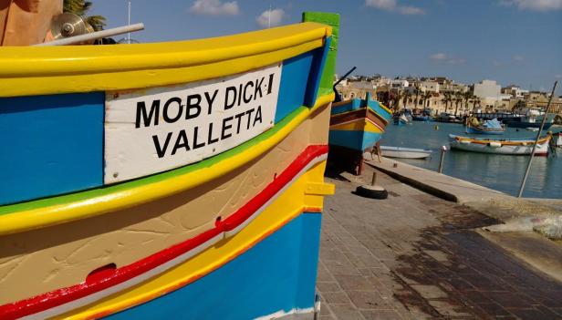 Ein buntes Fischerboot mit dem Namen „Moby Dick I Valletta“ liegt im Hafen.
