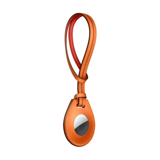 Ein orangefarbener Apple AirTag von Hermès mit einem Lederband.