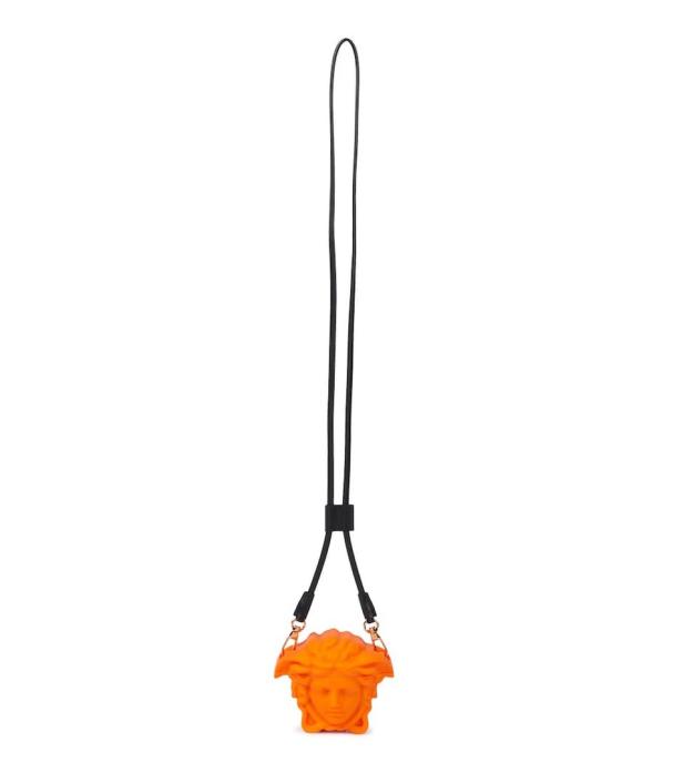 Eine orangefarbene Versace Medusa-Halskette mit schwarzer Kordel.