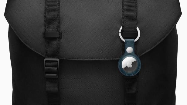 Ein Apple AirTag hängt an einer schwarzen Stofftasche.