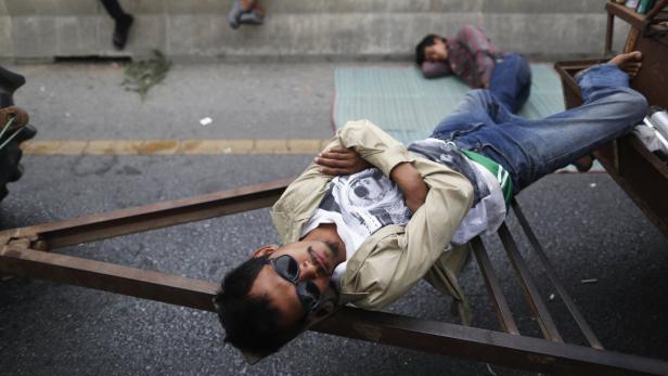 Zwei Männer ruhen sich auf einem Anhänger und einer Matte im Freien aus.