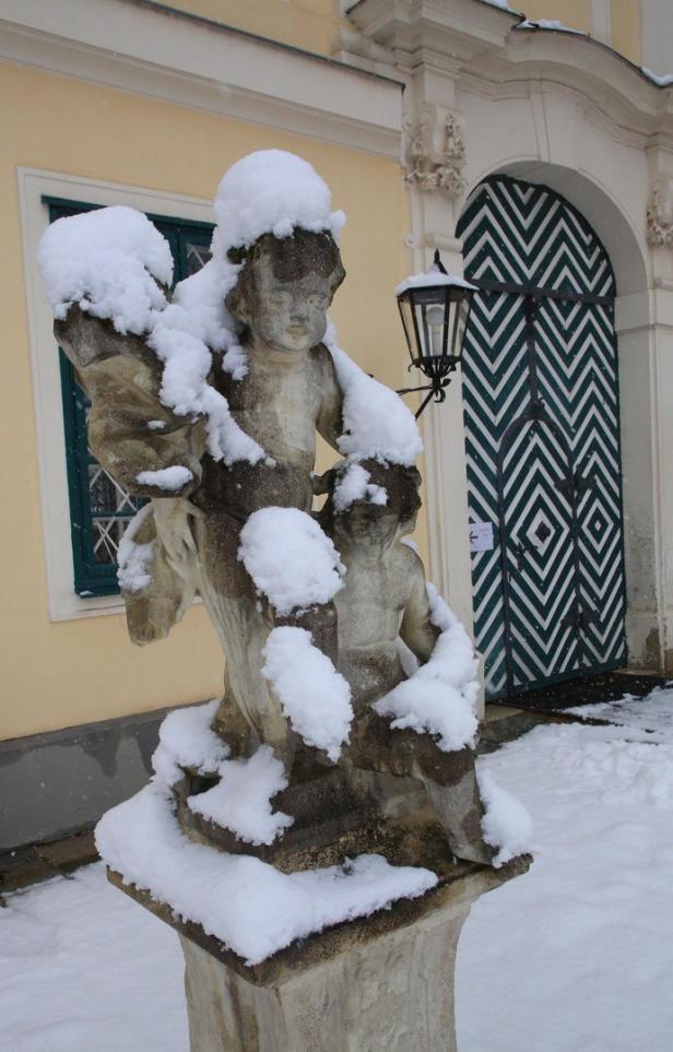 Eine mit Schnee bedeckte Skulptur von zwei Kindern vor einem Gebäude.