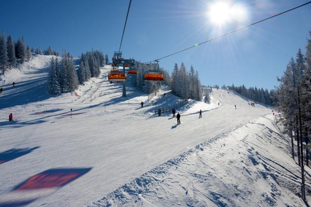 Eine Skipiste mit Skifahrern und einem Sessellift an einem sonnigen Tag.