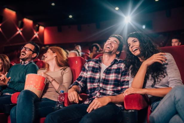 Eine Gruppe von Freunden lacht im Kino.
