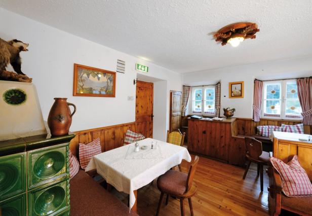 Ein traditionell eingerichtetes Esszimmer mit Kachelofen und Holztäfelung.