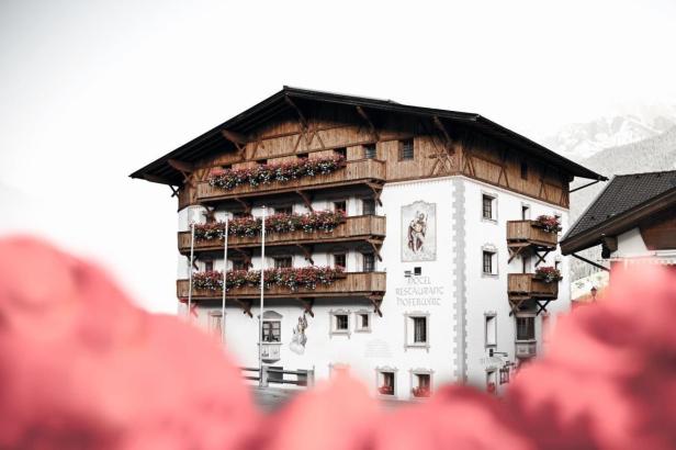 Das Hotel Restaurant Hoferwirt mit blumengeschmückten Balkonen in den Alpen.