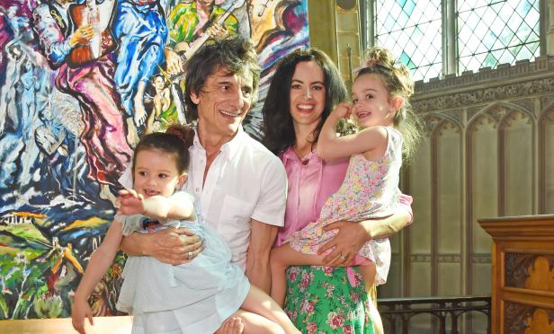 Ronnie Wood mit seiner Frau und seinen Zwillingstöchtern vor einem Gemälde.