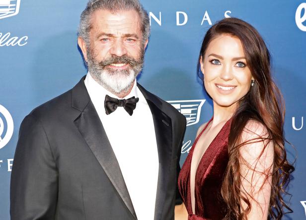 Mel Gibson posiert mit einer jungen Frau auf einer Veranstaltung.