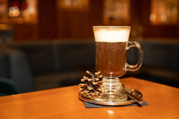 Ein Glas Irish Coffee mit einer Tannenzapfen-Dekoration auf einem Tisch.