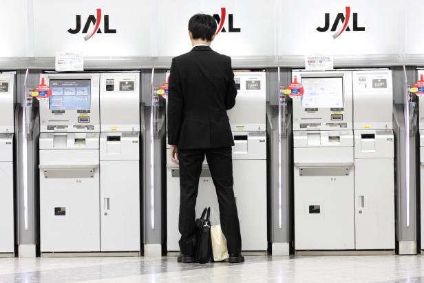 Ein Mann in Anzug benutzt einen JAL-Automaten.