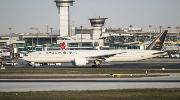 Eine Saudia-Boeing 777 rollt auf einer Startbahn vor einem Flughafentower.