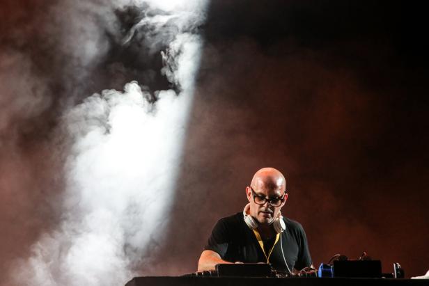Ein Mann mit Brille und Kopfhörern steht vor einem Mischpult im Nebel.