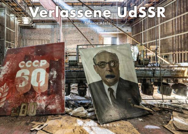 In einer verlassenen Fabrikhalle stehen ein Plakat mit der Aufschrift „CCCP 60“ und ein Porträt von Michail Gorbatschow.