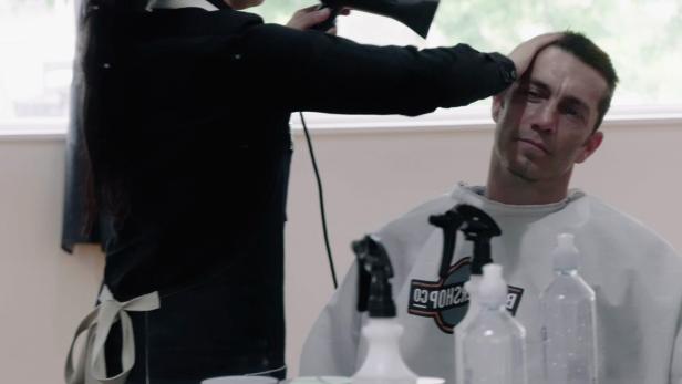 Ein Mann bekommt in einem Friseursalon die Haare geföhnt.